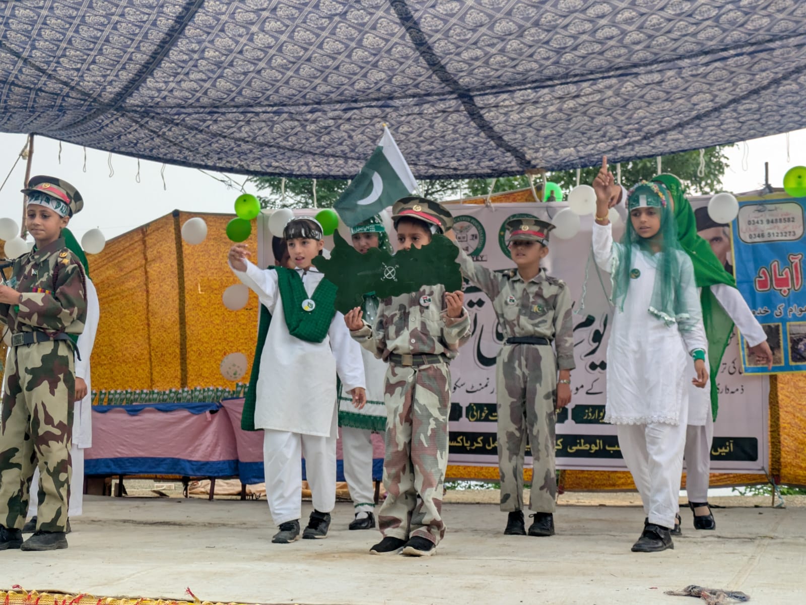Students on stage with a Pakistan flag and map cutout